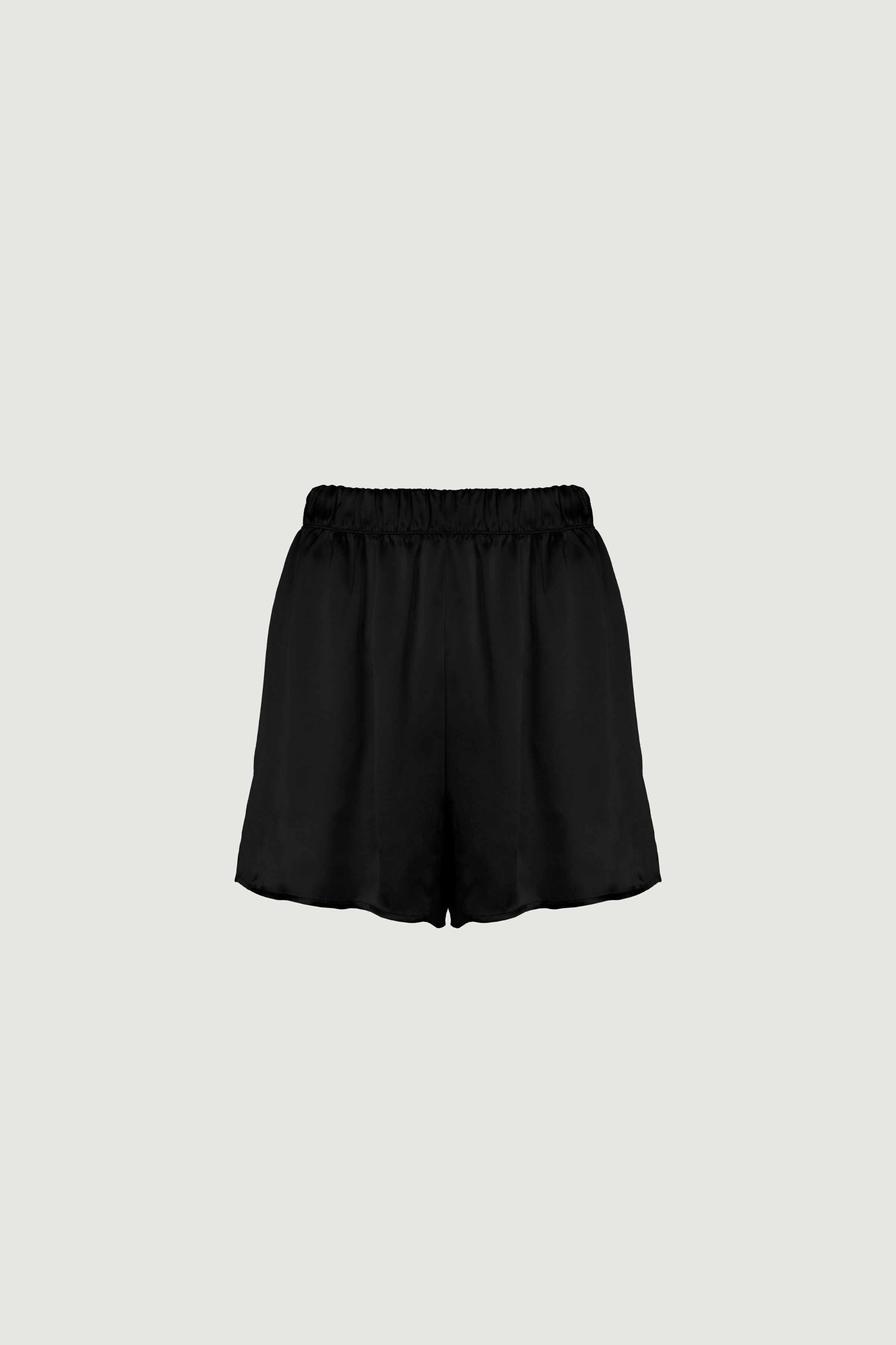 Black organic silk shorts with elastic waistband, side pockets and relaxed longer cut, fluid drape and soft texture, front view