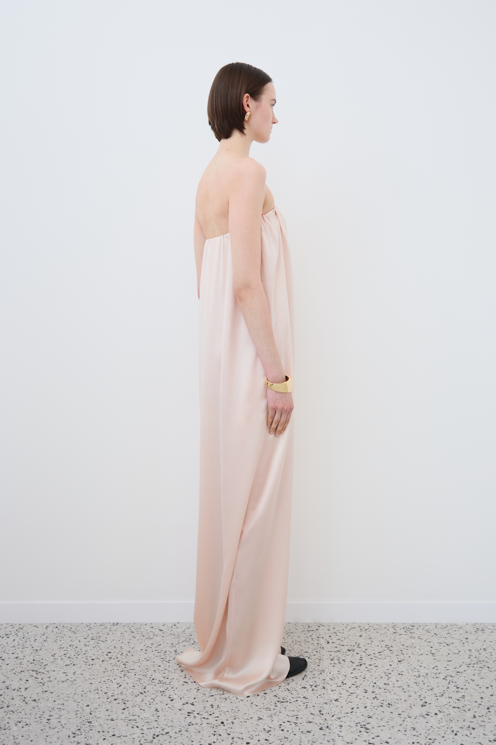 Side view of the HERTH Erin off-shoulder slip dress in Whisper Pink — fluid silhouette crafted from soft GOTS-certified organic silk, embodying minimal and refined sustainable womenswear.