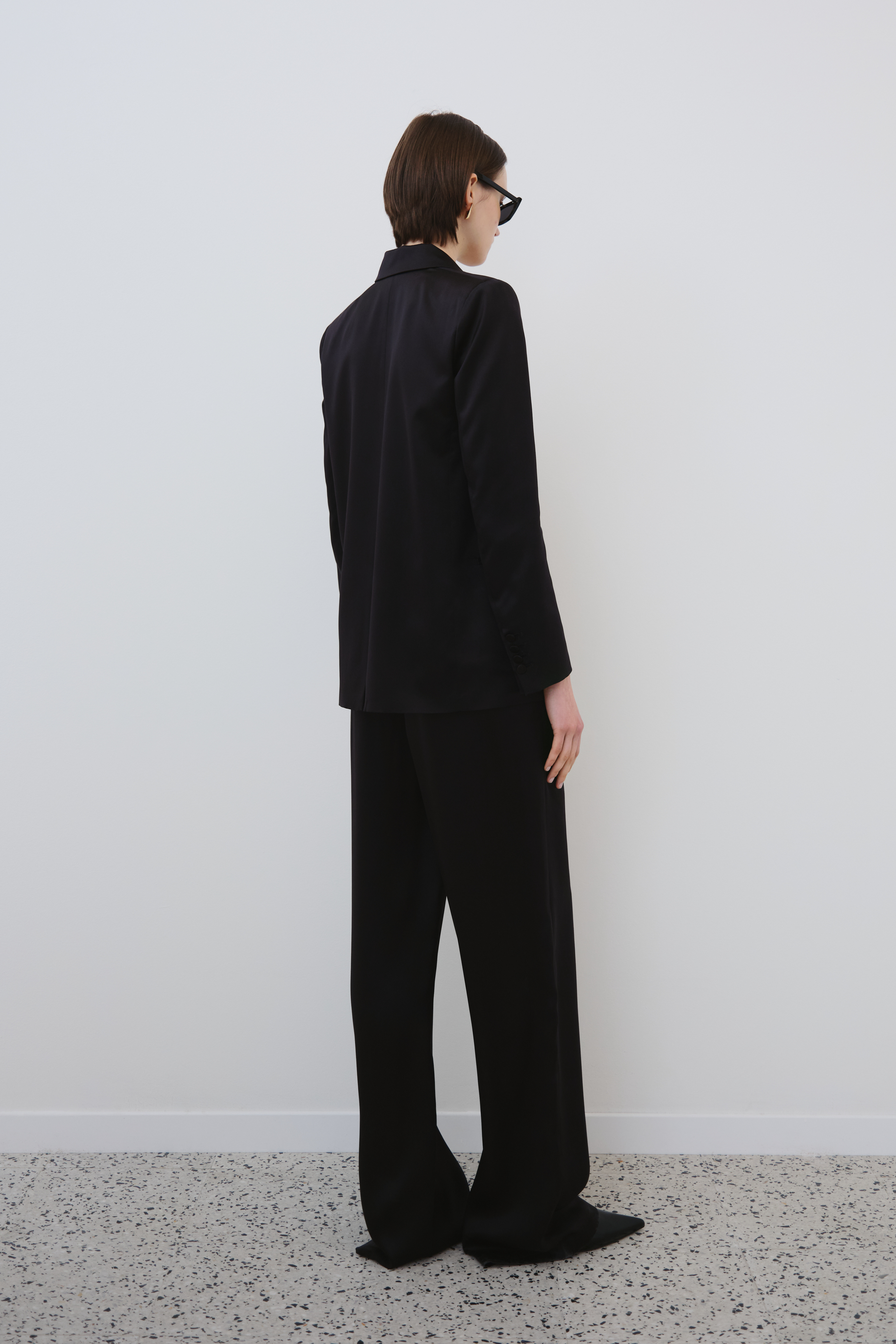 Model wearing the HERTH Joy organic silk trousers in black with the Uma silk blazer, back view.