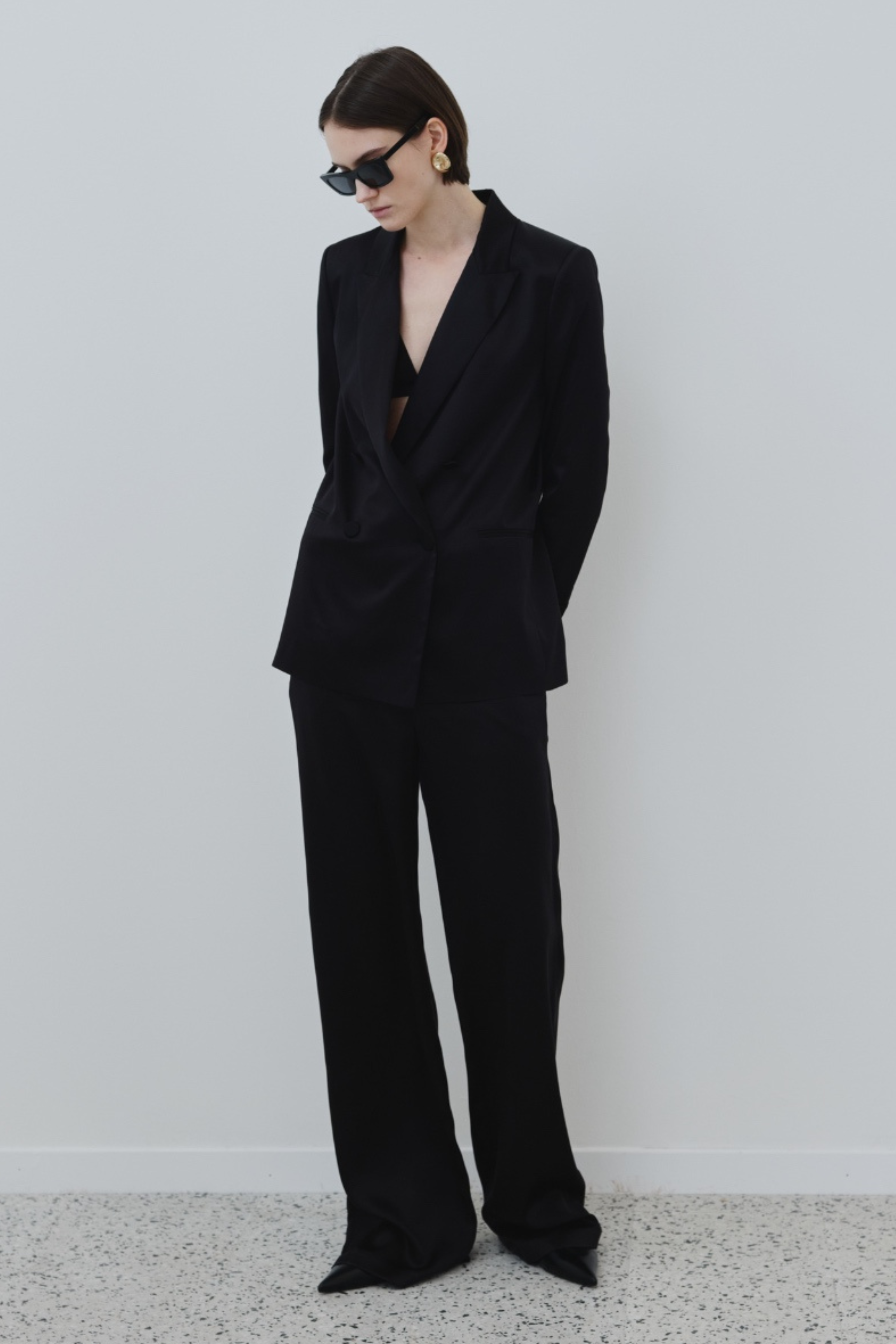 Model wearing the HERTH Joy organic silk trousers in black paired with the Uma silk blazer, front view.