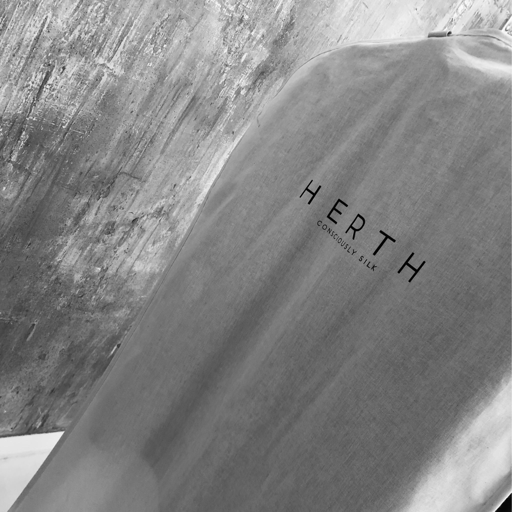 organic silk garment bag with HERTH logo, representing sustainable craftsmanship made in Italy