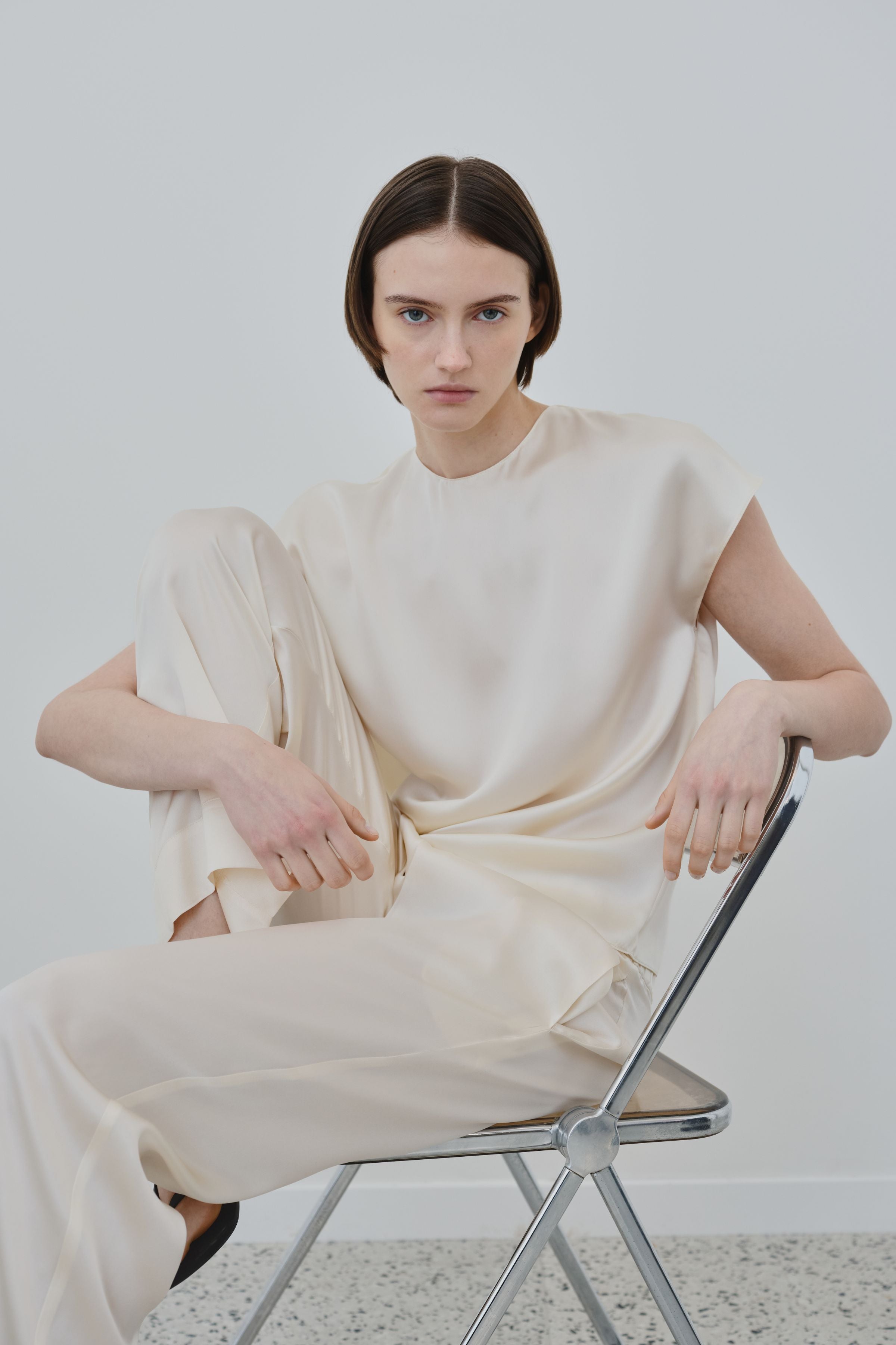 Model wearing ivory organic silk Zeno trousers by HERTH, fluid wide-leg silhouette styled in a refined womenswear look, made in Italy