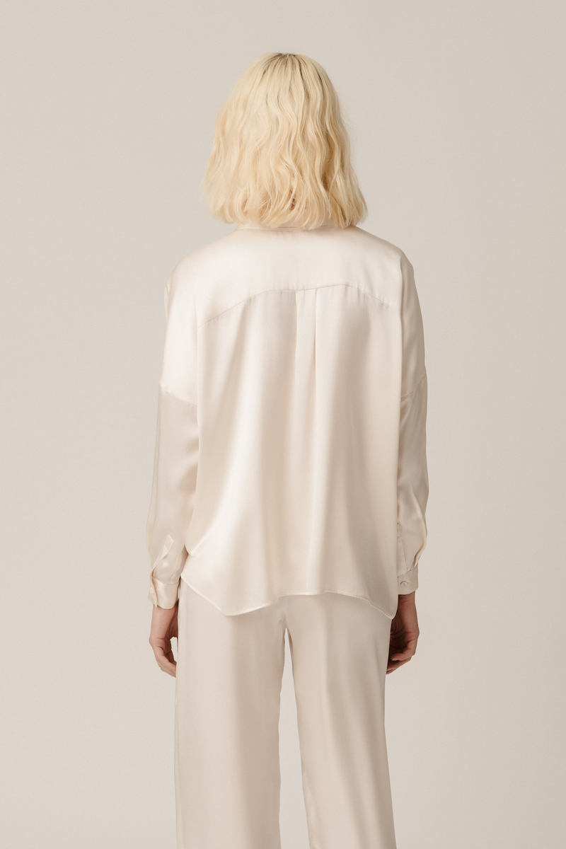Model wearing Tara shirt and Zeno trousers almond organic silk womenswear set, back view by HERTH