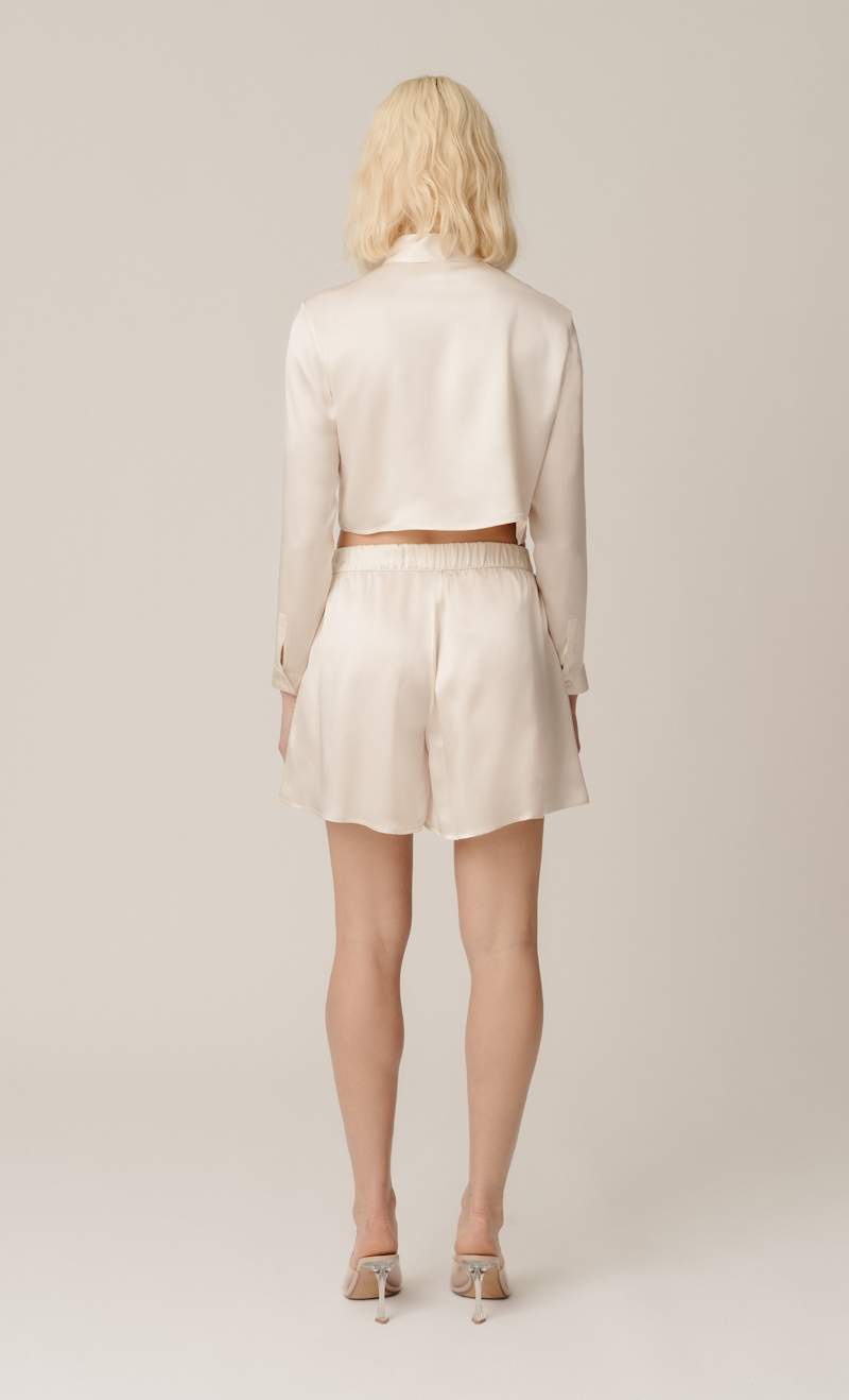 Model wearing Tea cropped shirt and Hani shorts in almond — sustainable organic silk womenswear set by HERTH, styled for effortless elegance.