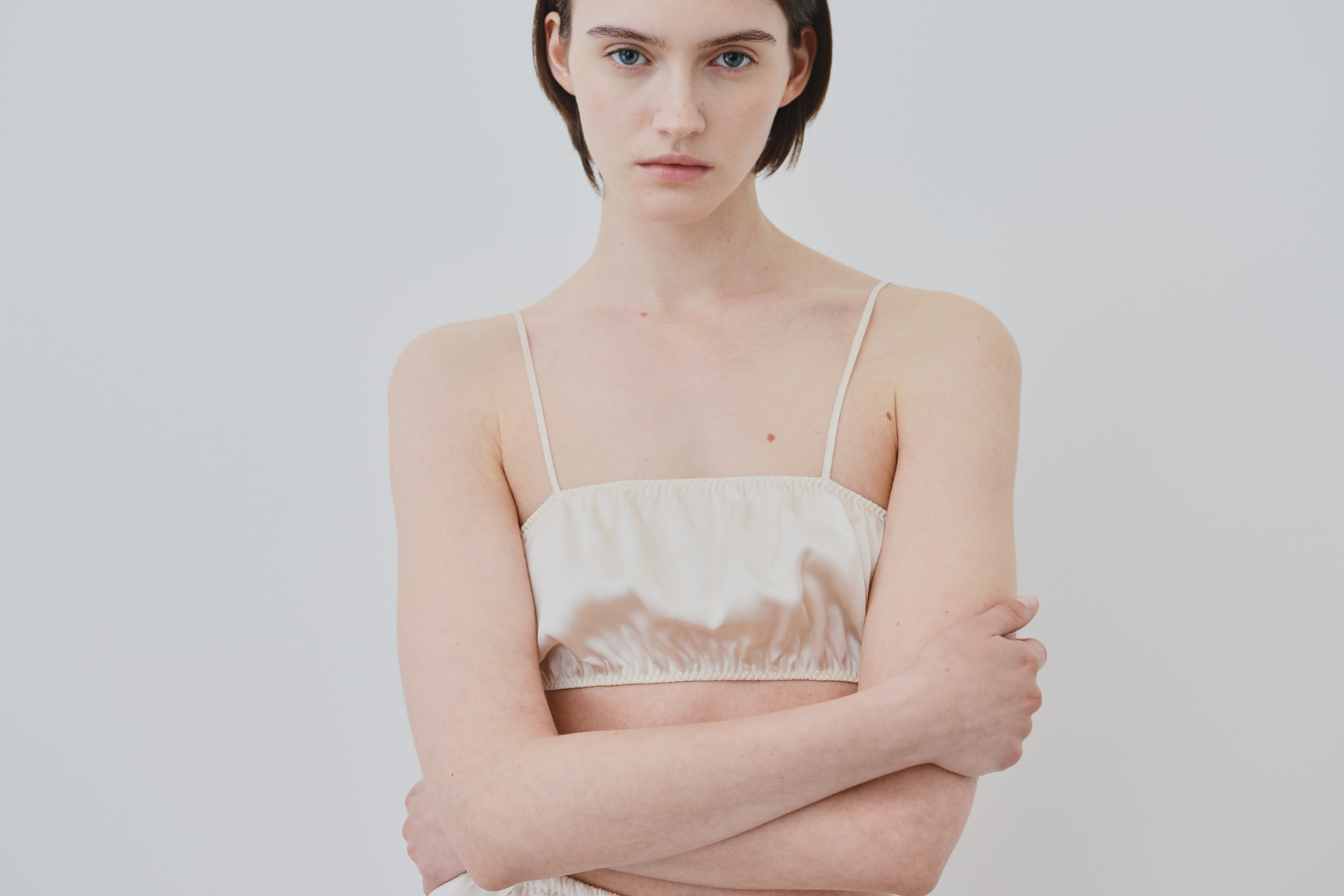 Model wearing HERTH organic silk bralette in a minimal studio setting, showcasing the softness and purity of premium sustainable lingerie