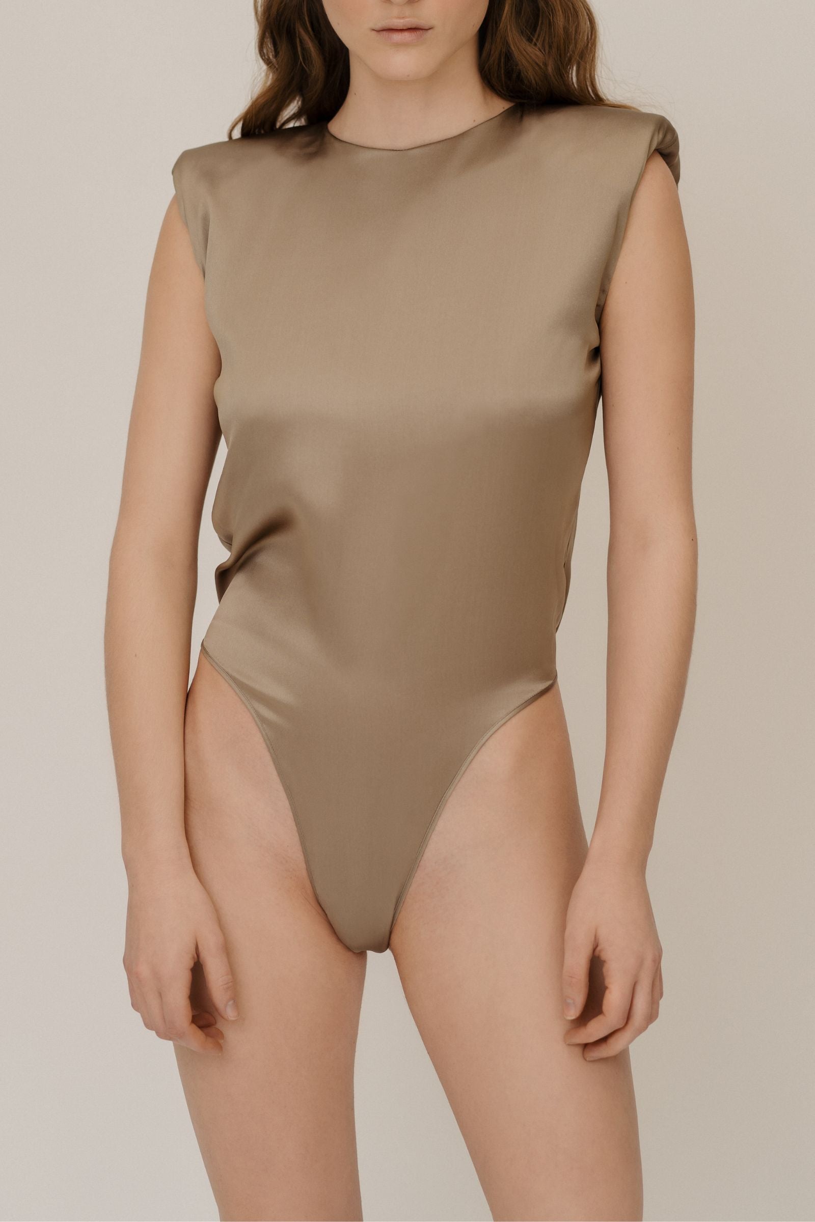 Model wearing gold silk bodysuit crafted in Italy from organic silk sourced from GOTS-certified suppliers, featuring a minimal structured