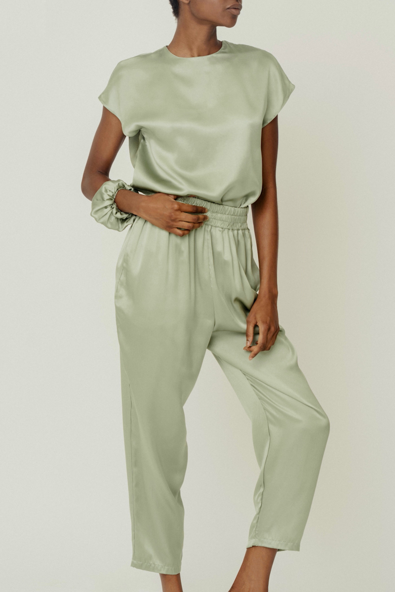 Model wearing HERTH’s Cora top, Roy trousers, and Edi scrunchie in Green Tea — timeless womenswear outfit in GOTS-certified organic silk.