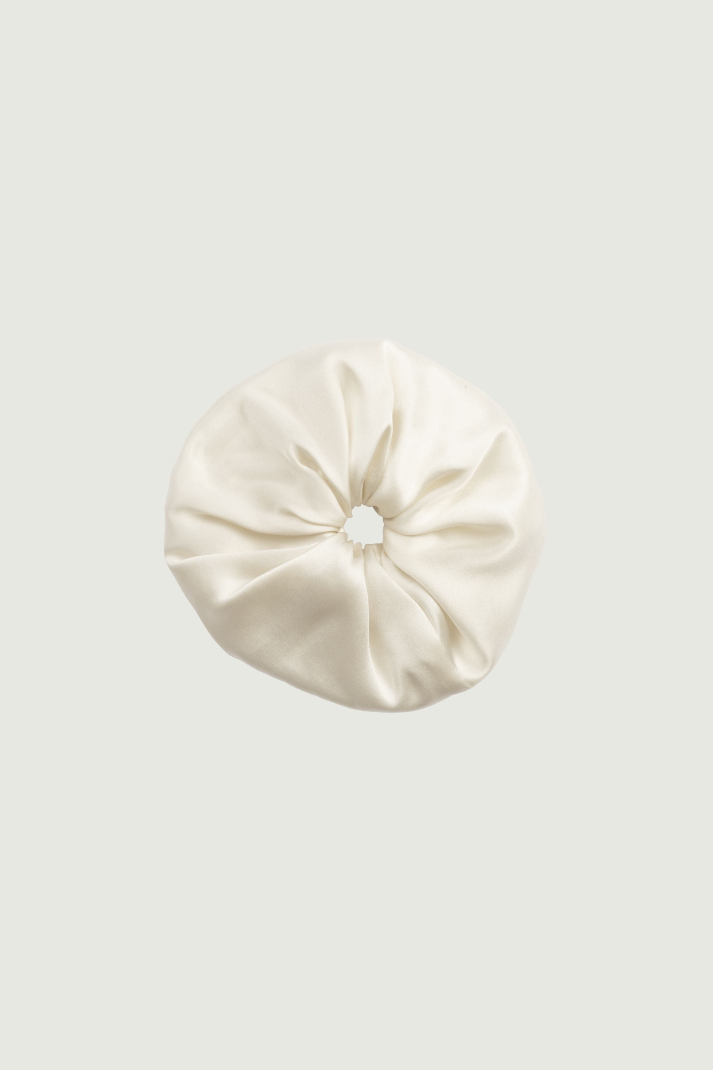 Almond silk scrunchie worn on the wrist, soft elastic hair tie