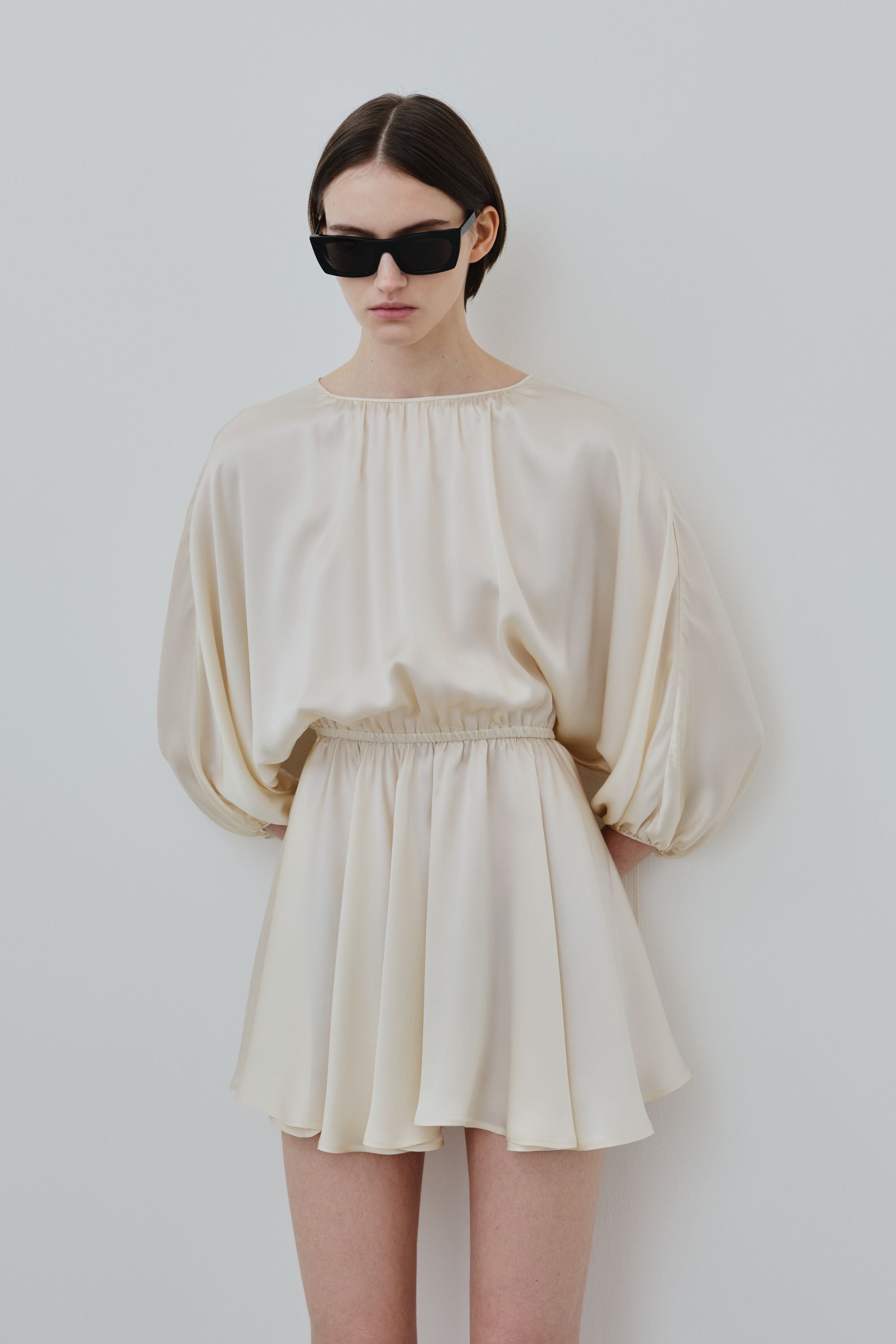 Back view of model wearing organic silk mini dress in almond, Ema dress, lifestyle shot