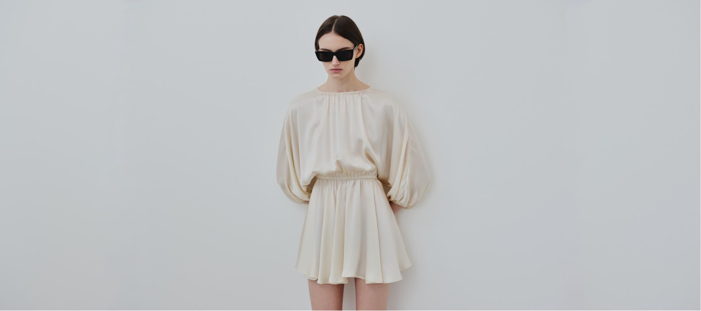 Model wearing the EMA silk dress in Almond, an elegant organic silk silhouette from HERTH.