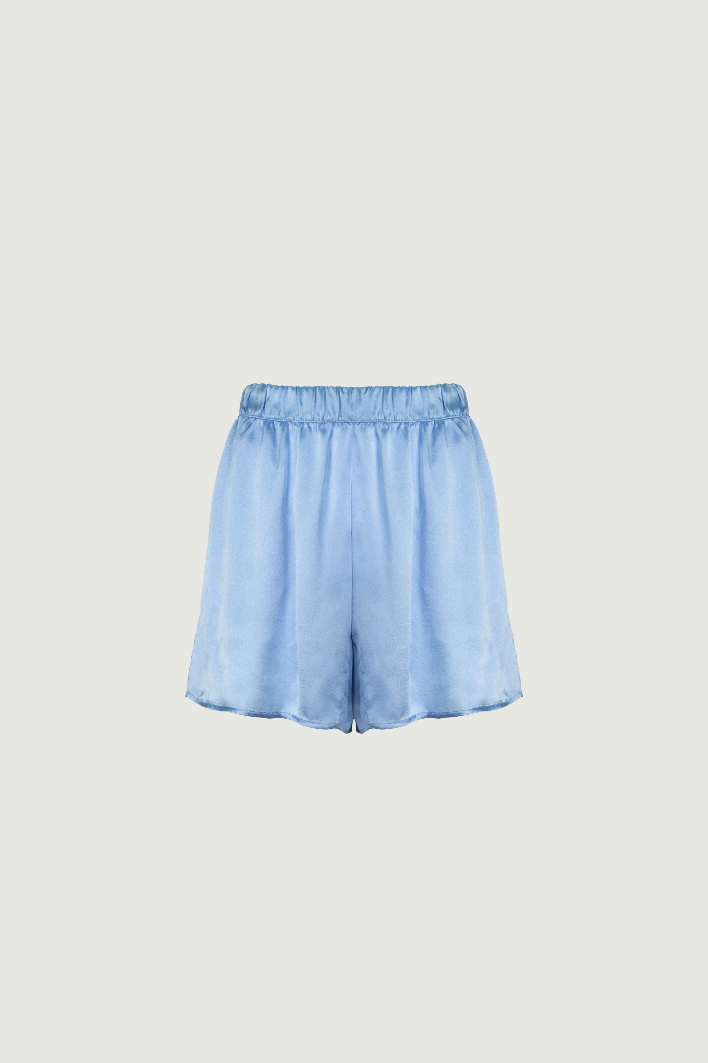 Sky blue organic silk shorts with elastic waistband, side pockets and loose longer fit, soft drape and relaxed silhouette, front view