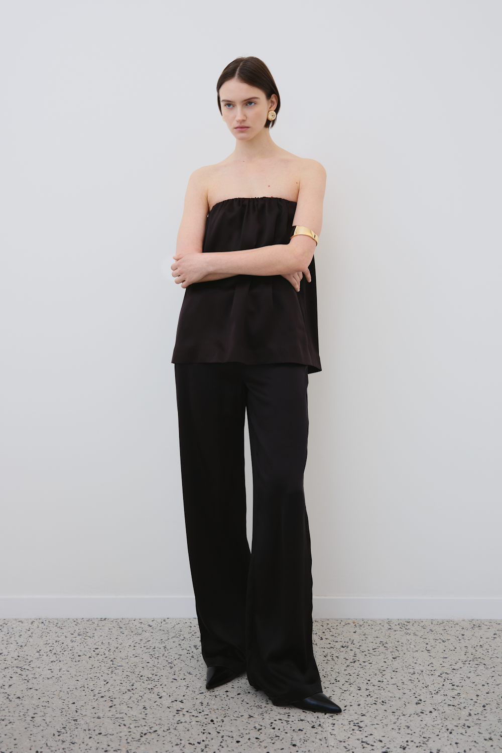 Front full-body view of the Gala strapless silk top in black paired with wide-leg pants - Luxury womenswear by HERTH.