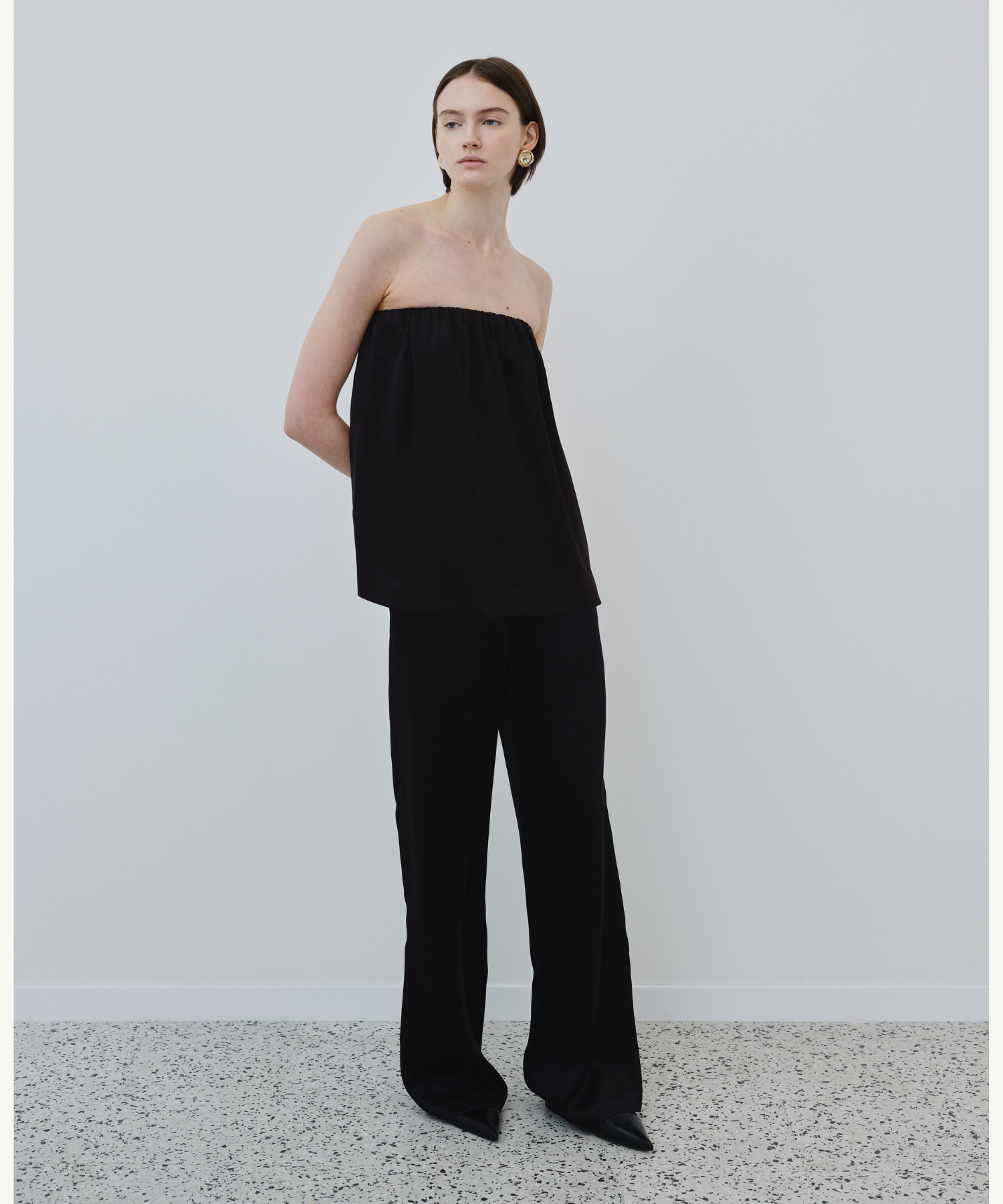 Model wearing HERTH Gala organic silk strapless top with Joy silk pants in black, sustainable luxury fashion essentials.