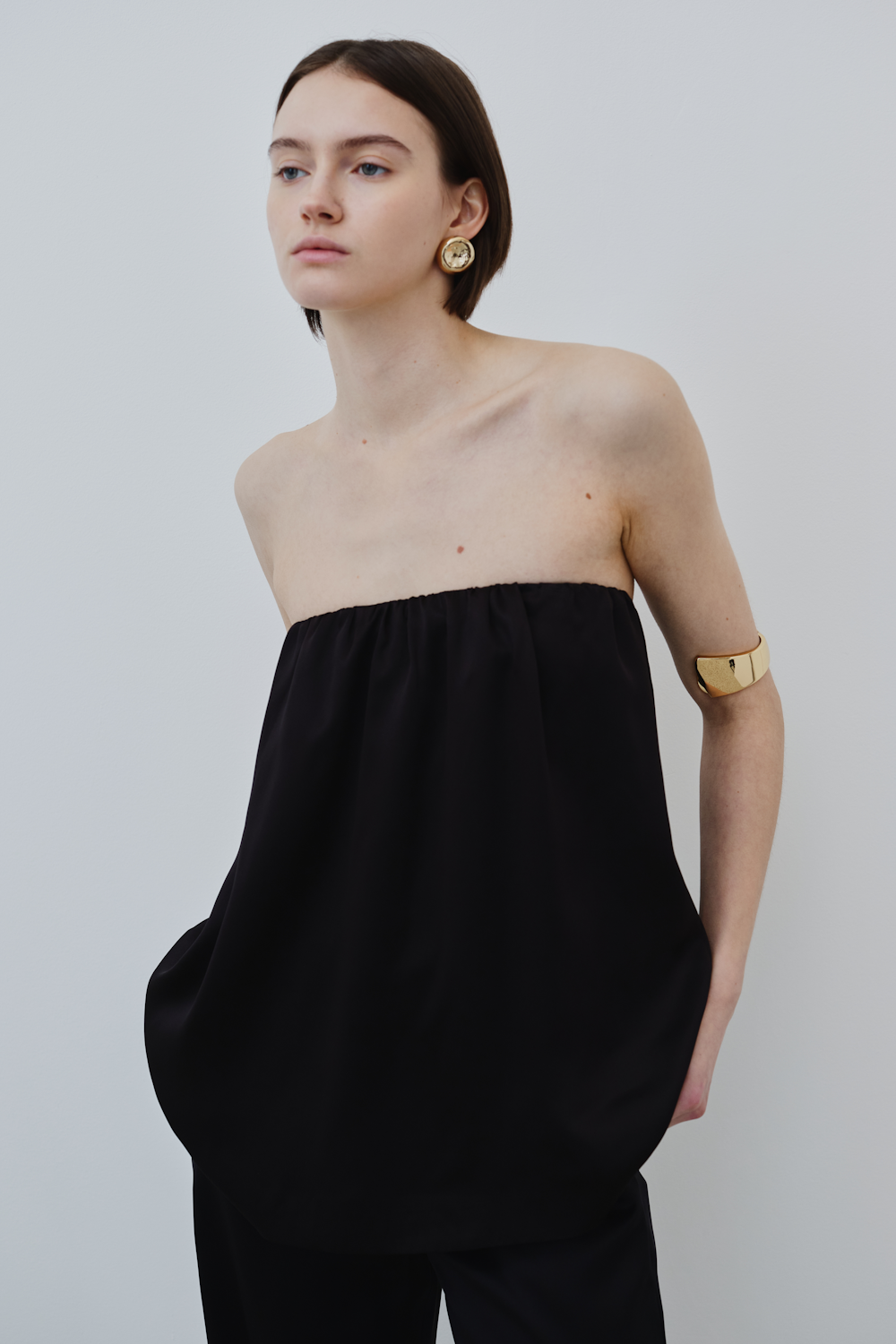 Woman wearing HERTH Gala strapless silk top in black organic silk — elegant womenswear piece with minimal design, perfect for timeless sustainable wardrobes.