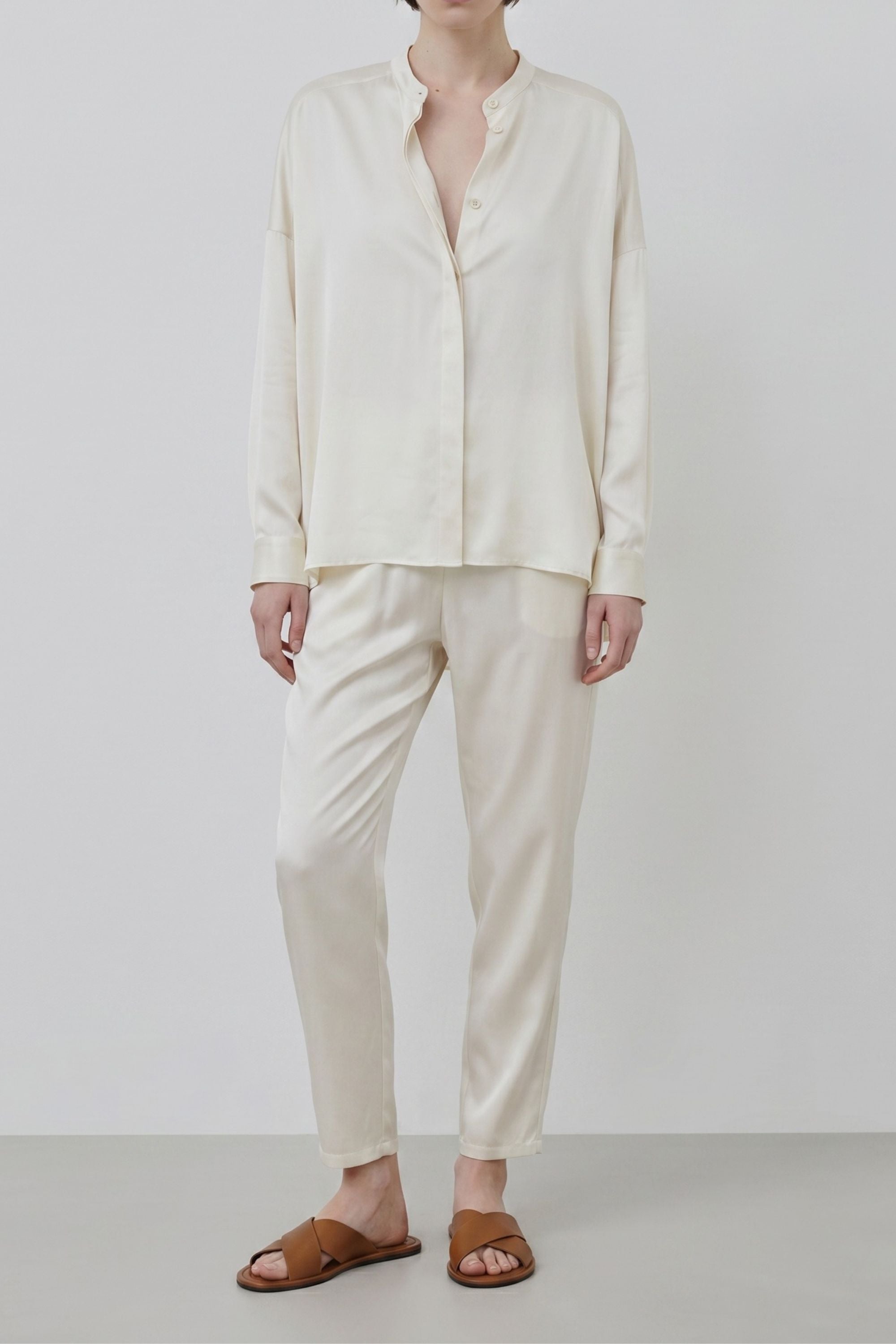 Ivory silk shirt worn with ankle-length trousers, organic silk garments crafted in Italy with clean and fluid silhouette