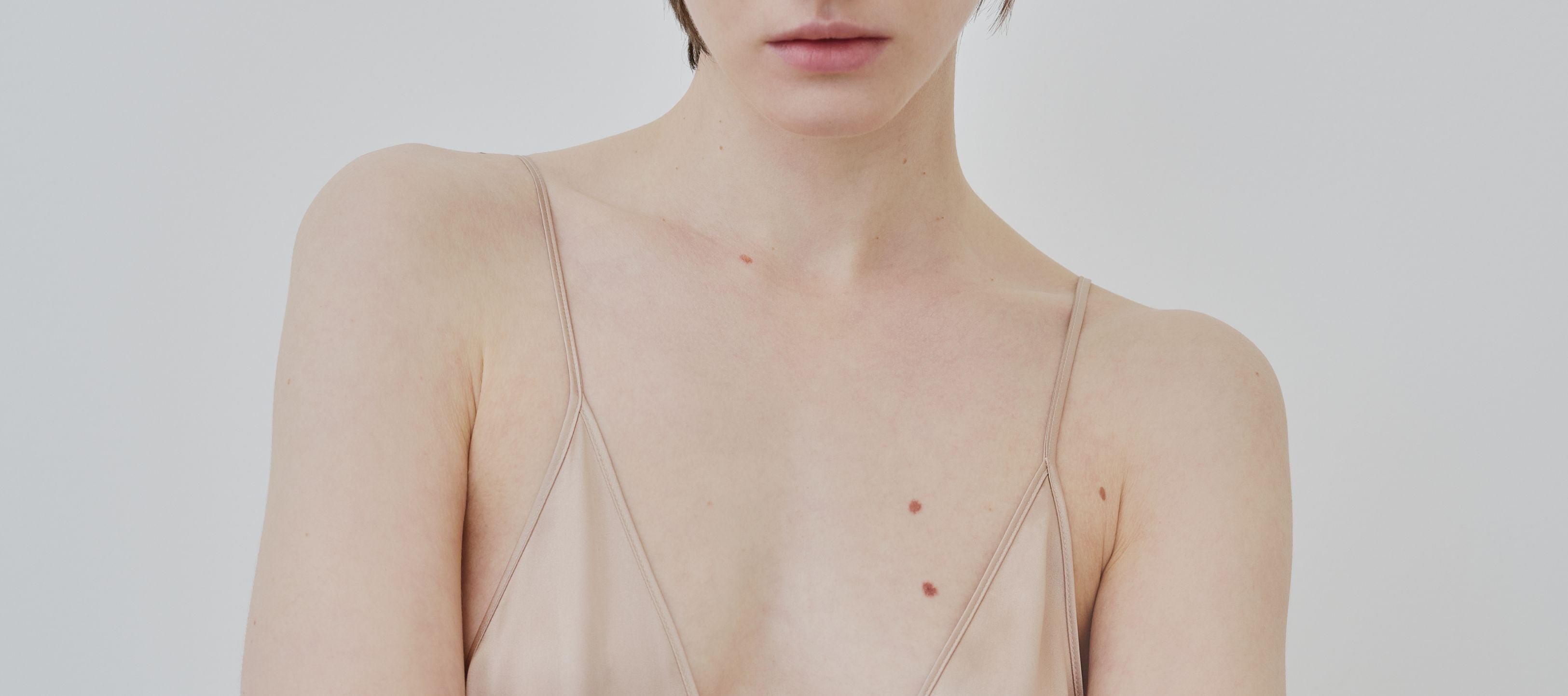 Close-up of HERTH organic silk Inez dress in almond, showing delicate texture and minimal straps