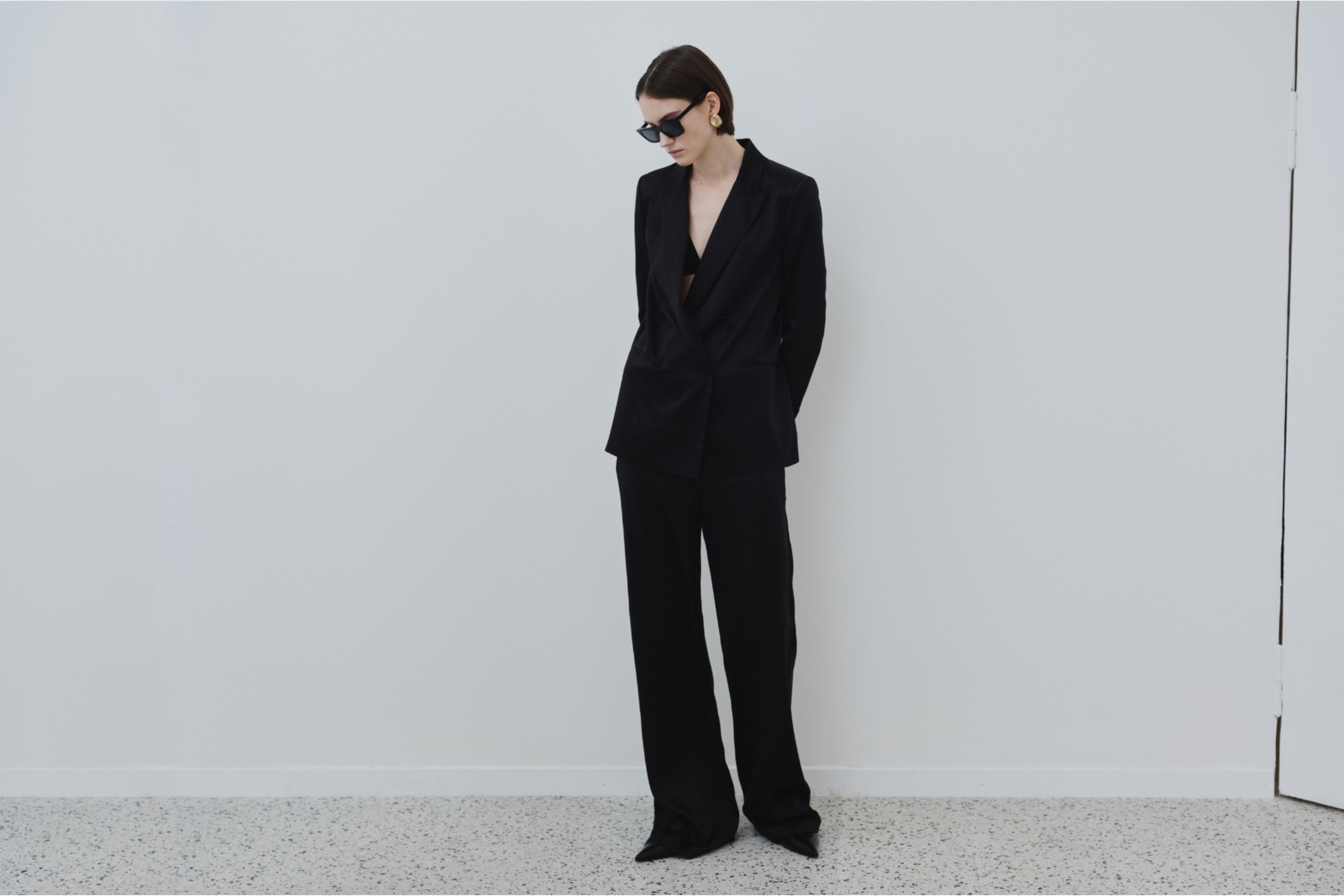 Model wearing HERTH organic silk Uma blazer with Ivy triangle bra and Joy trousers in black, tailored minimal styling