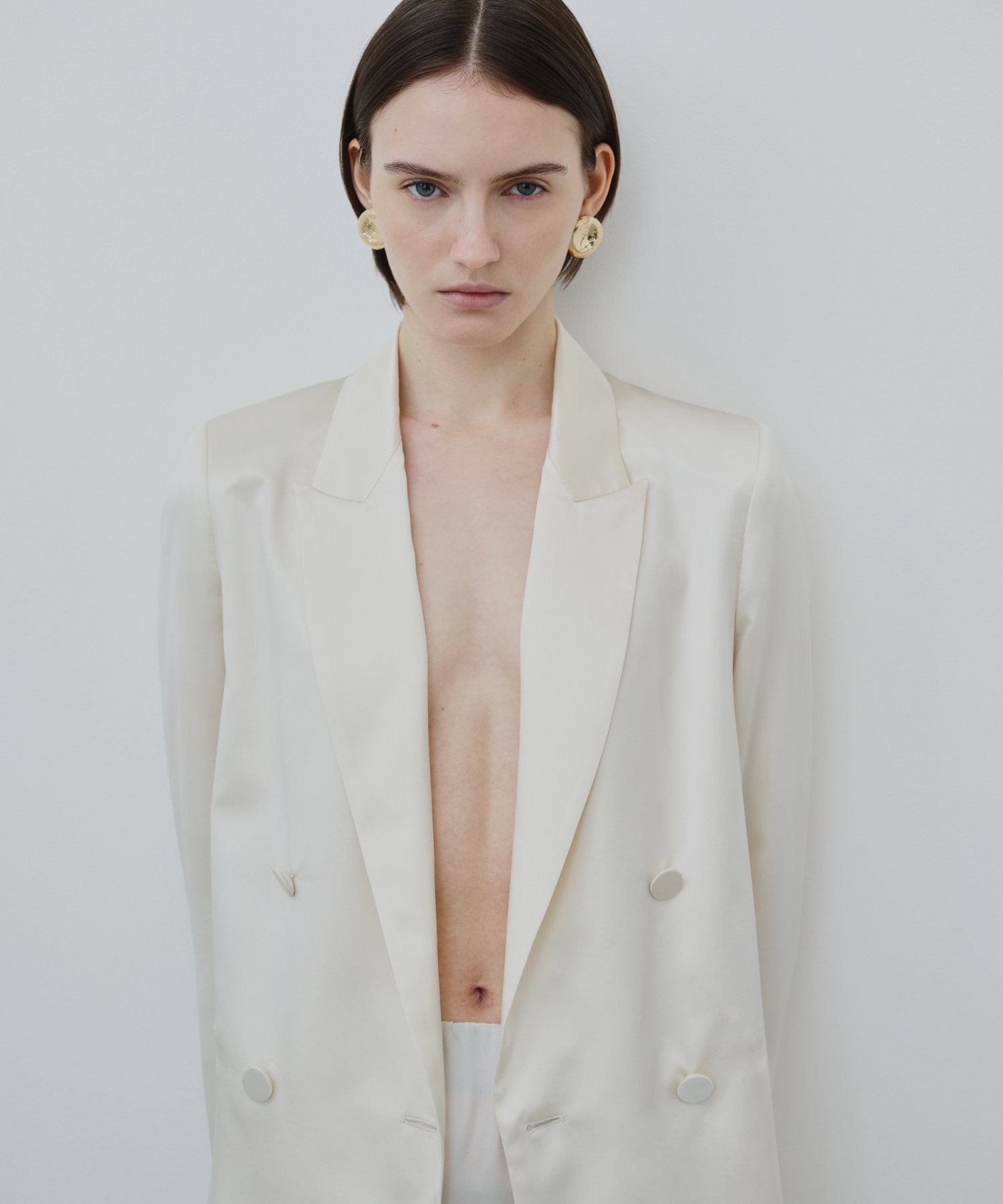 Model wearing HERTH organic silk Uma blazer and Noilde skirt in ivory, minimalist Italian design