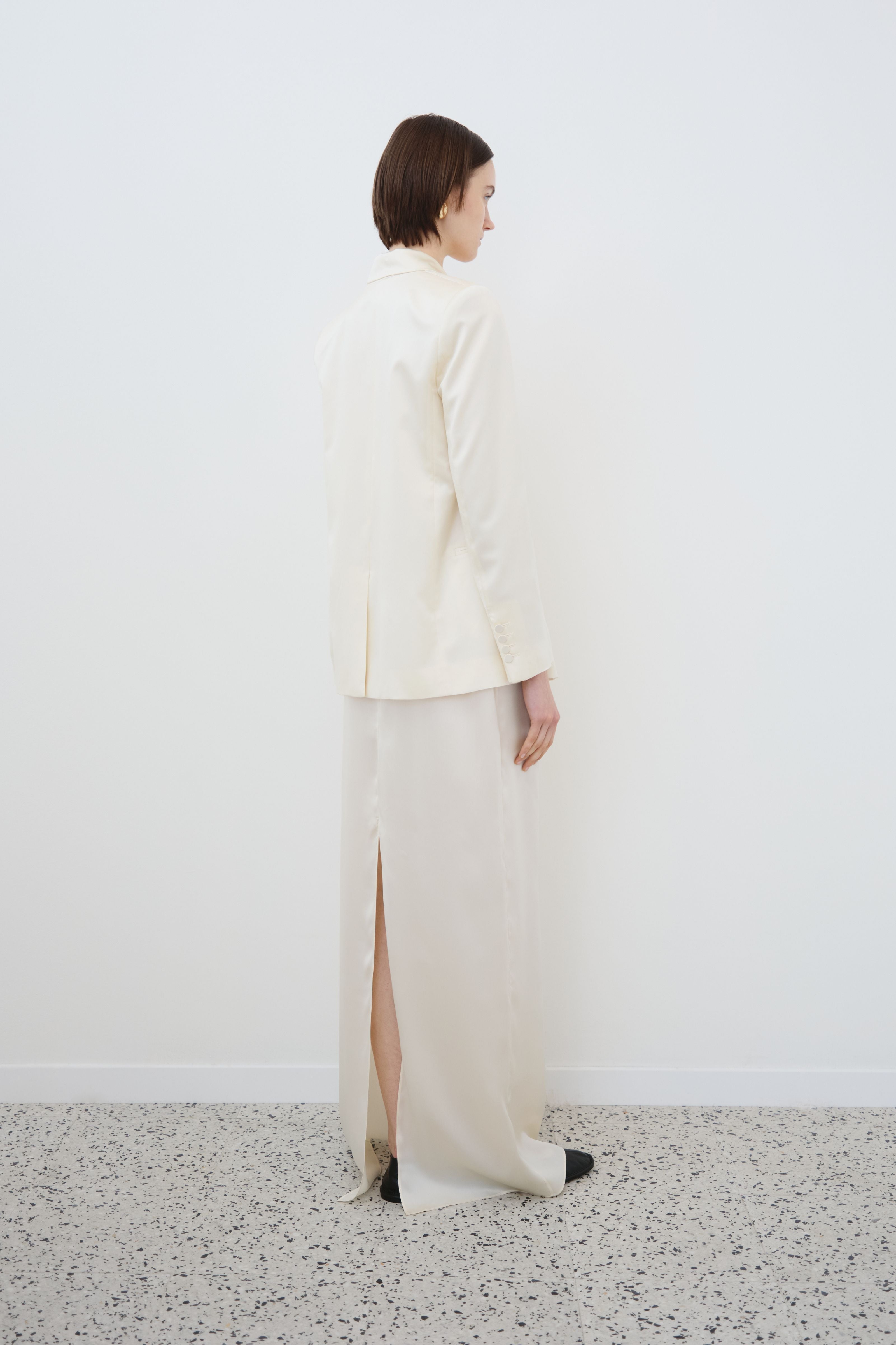 Model wearing the HERTH Uma organic silk blazer in Almond with the Nilde organic silk skirt, back view.