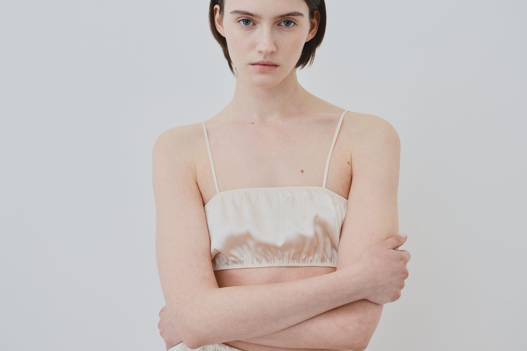 Model wearing organic silk bandeau lingerie in ivory, crafted in Italy by HERTH