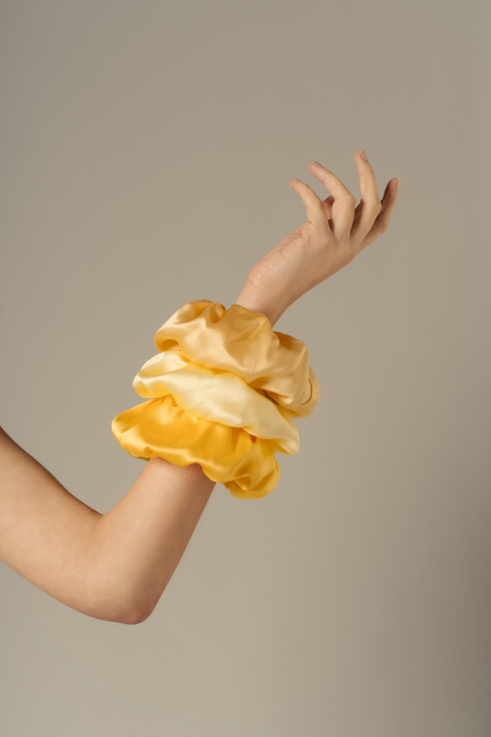 Editorial image featuring Edi scrunchies in Desert, Butter Yellow, and Mango — sustainable organic silk hair accessories styled for summer by HERTH.